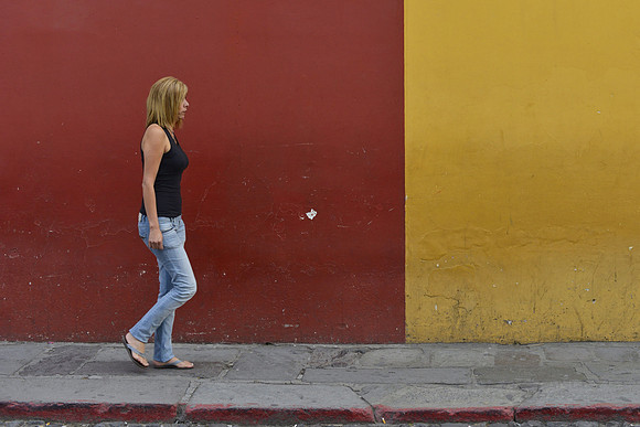 The colorful wall of Antigua, Guatemala as people walk by. Photography by Peter Stanley, 2012